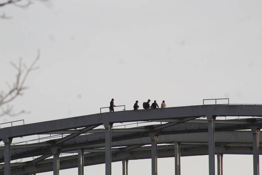 Persoon op bogen van brug, vele hulpdiensten aanwezig