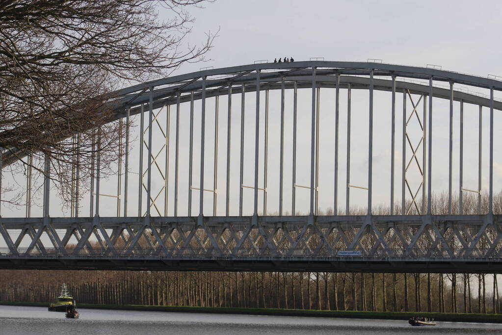 Persoon op bogen van brug, vele hulpdiensten aanwezig