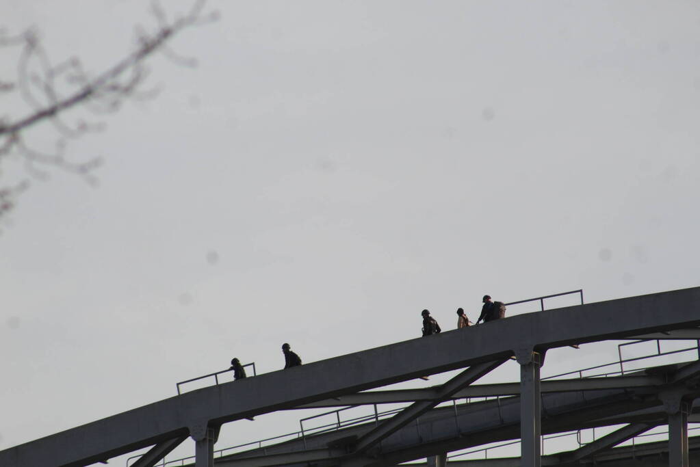 Persoon op bogen van brug, vele hulpdiensten aanwezig