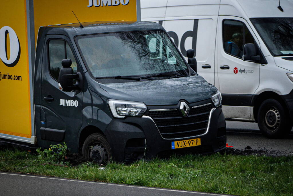 Jumbo bezorger raakt met bakwagen van weg en komt vast te zitten