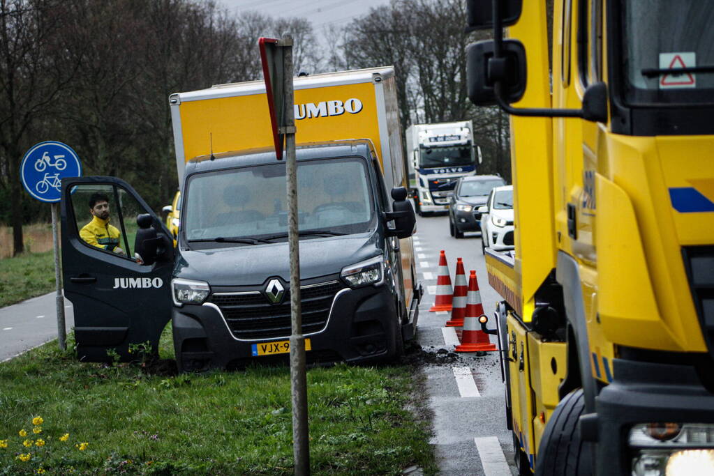 Jumbo bezorger raakt met bakwagen van weg en komt vast te zitten
