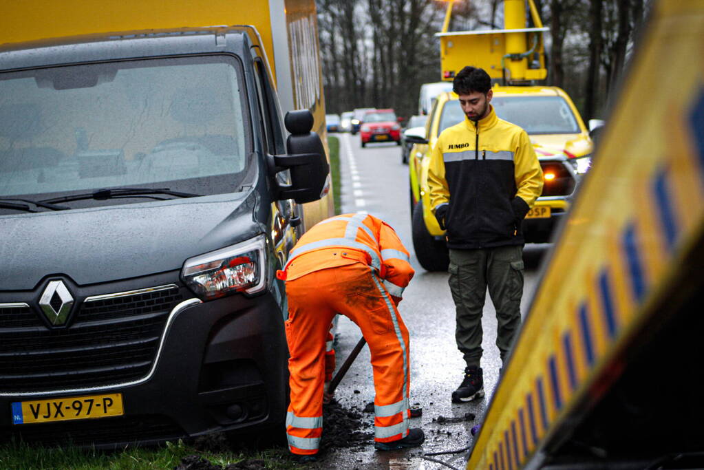 Jumbo bezorger raakt met bakwagen van weg en komt vast te zitten