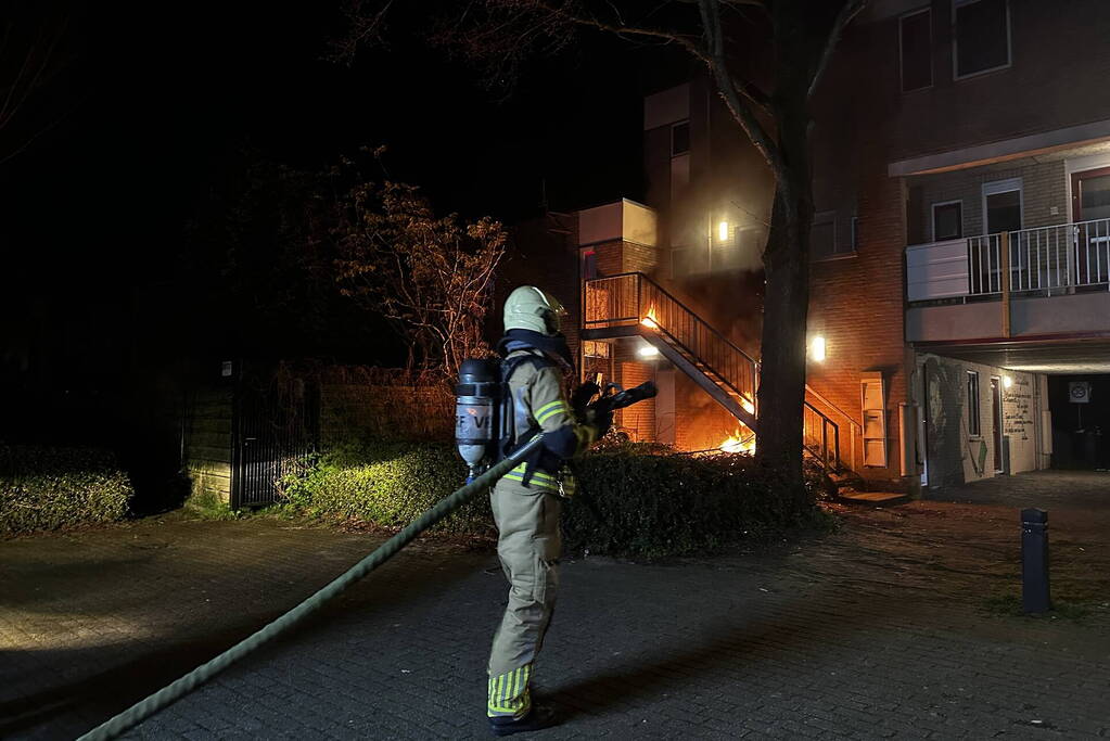 Brandweer blust brandende container onder trap