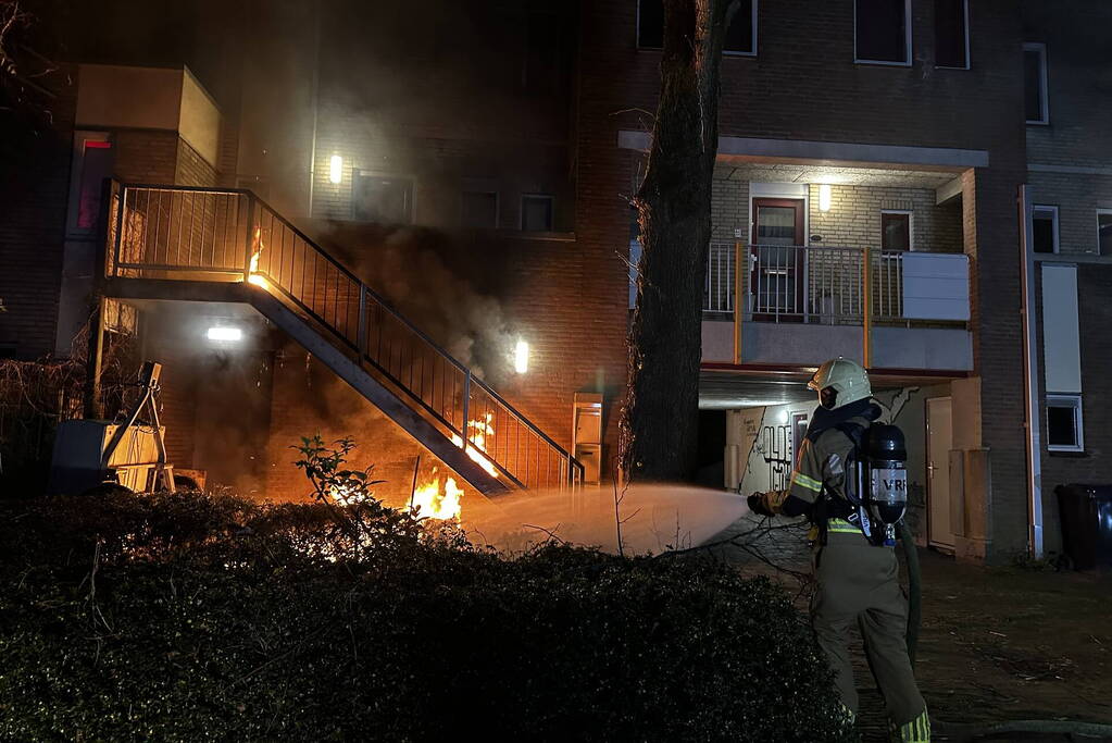 Brandweer blust brandende container onder trap