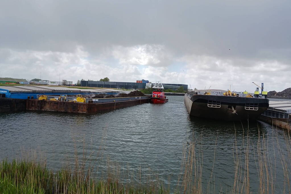 Brandweerboot inspecteert dampende duwbak
