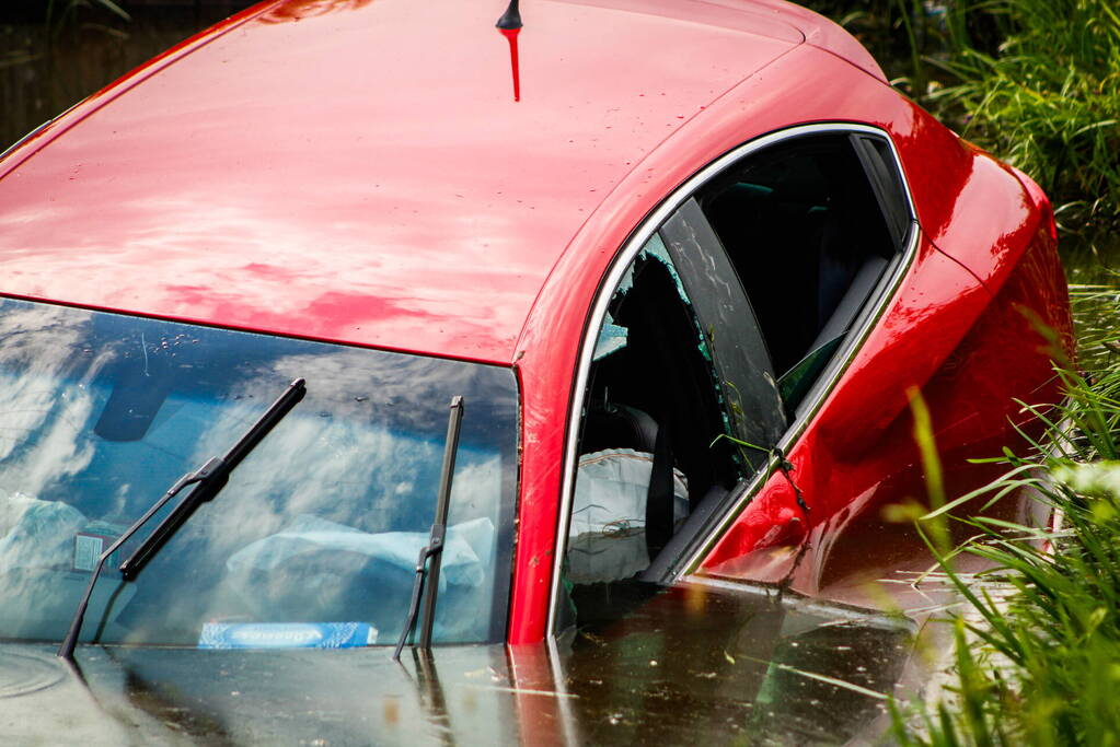 Omstanders helpen personen uit auto die te water raakte
