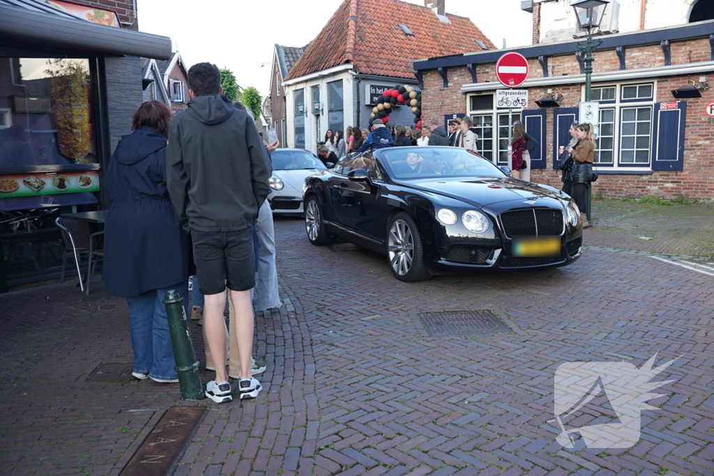 Leerlingen komen in bijzondere auto's aan bij examenfeest
