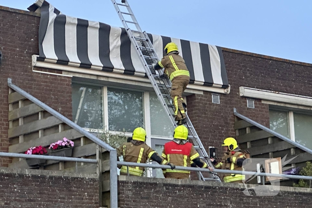 Zonnescherm waait kapot, brandweer ingezet