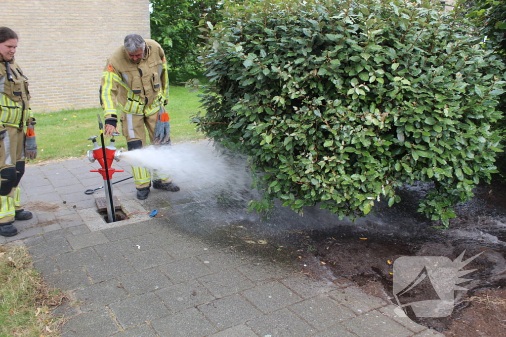 Brandweer blust buitenbrand met water uit brandkraan