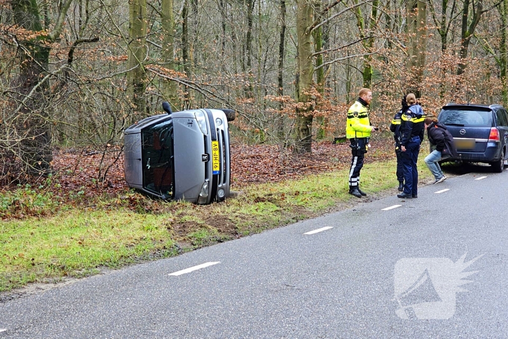 Auto belandt op zijkant naast weg