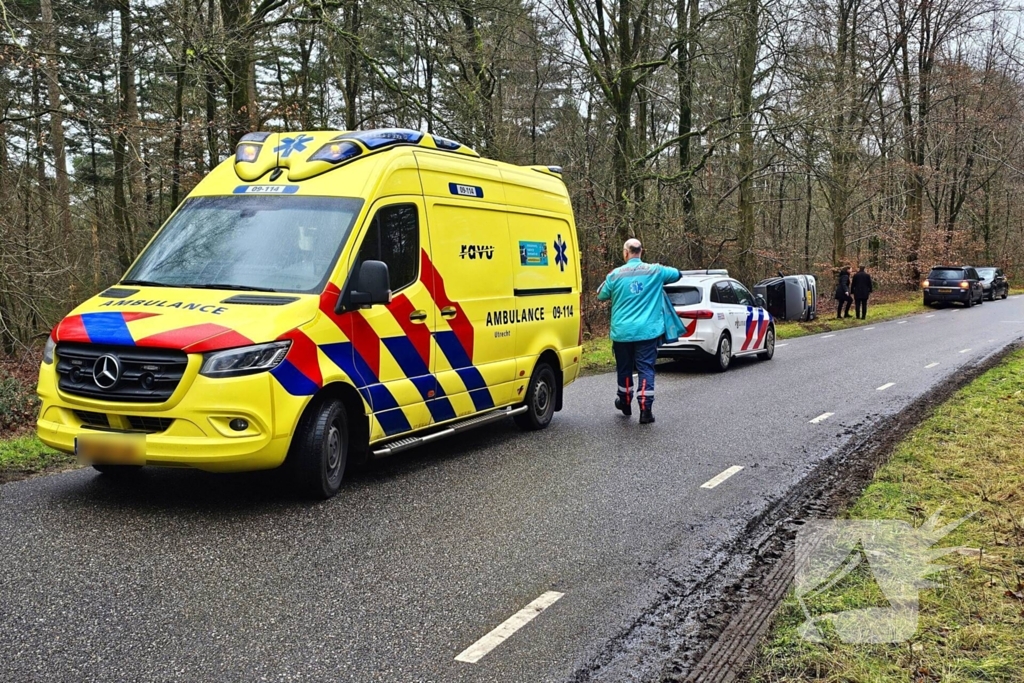 Auto belandt op zijkant naast weg