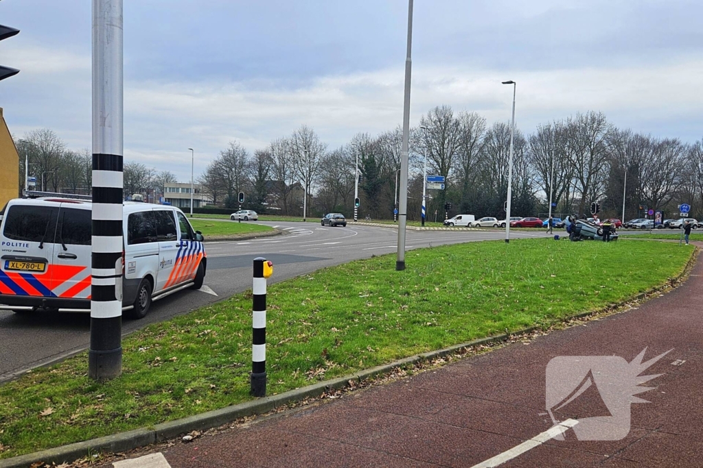 Auto belandt op kop naast rotonde