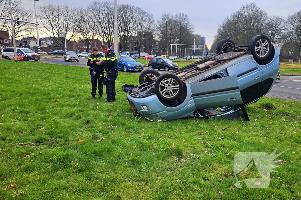 Auto belandt op kop naast rotonde