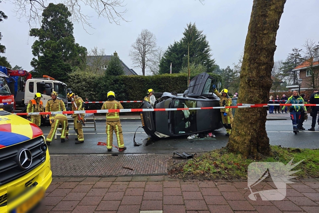 Auto belandt op zijn kant na botsing tegen boom
