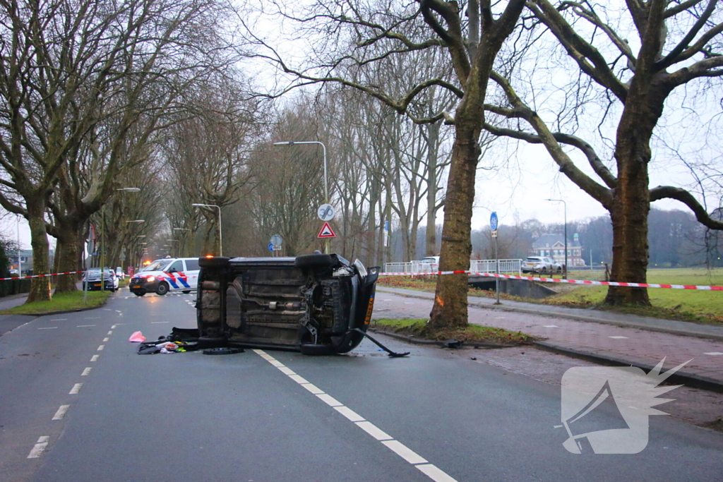 Auto belandt op zijn kant na botsing tegen boom