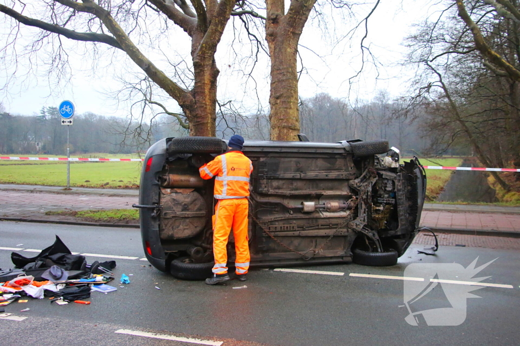 Auto belandt op zijn kant na botsing tegen boom
