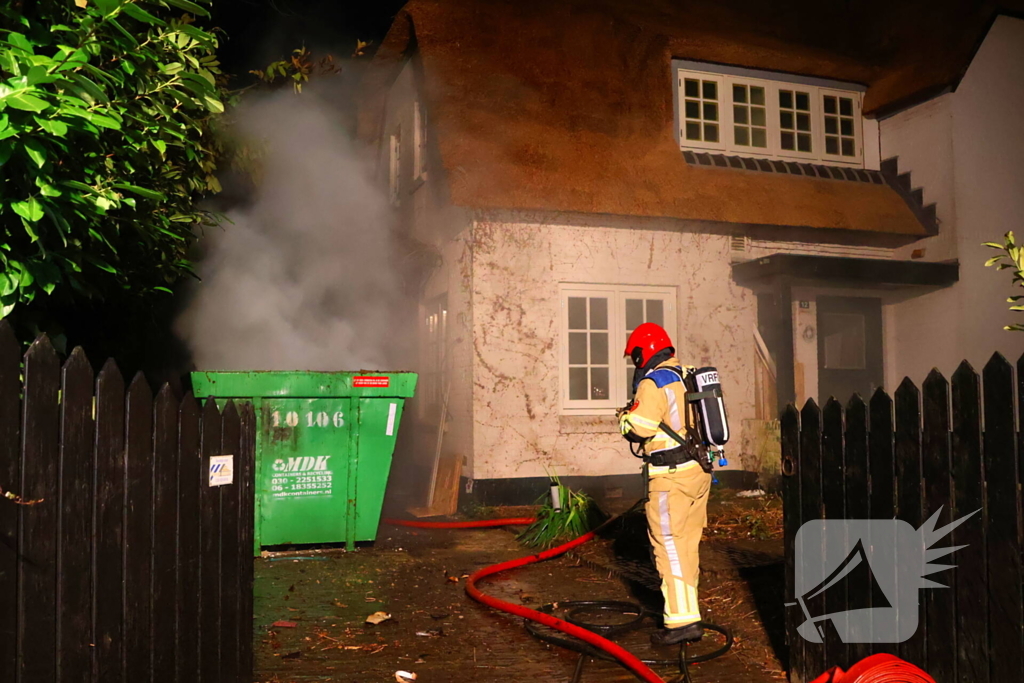 Bouwcontainer vat vlam naast woning met rietendak