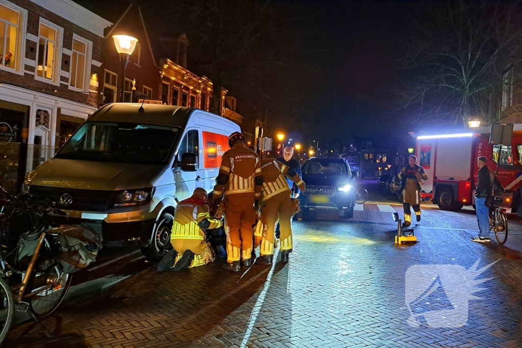 Persoon bekneld onder bestelbus