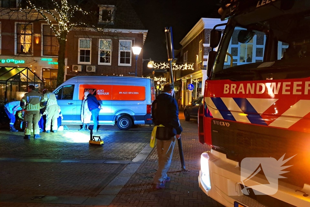 Persoon bekneld onder bestelbus