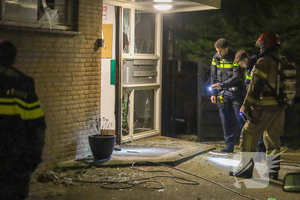 Explosie bij portiek van flatgebouw, brandweer blust vuurhaard