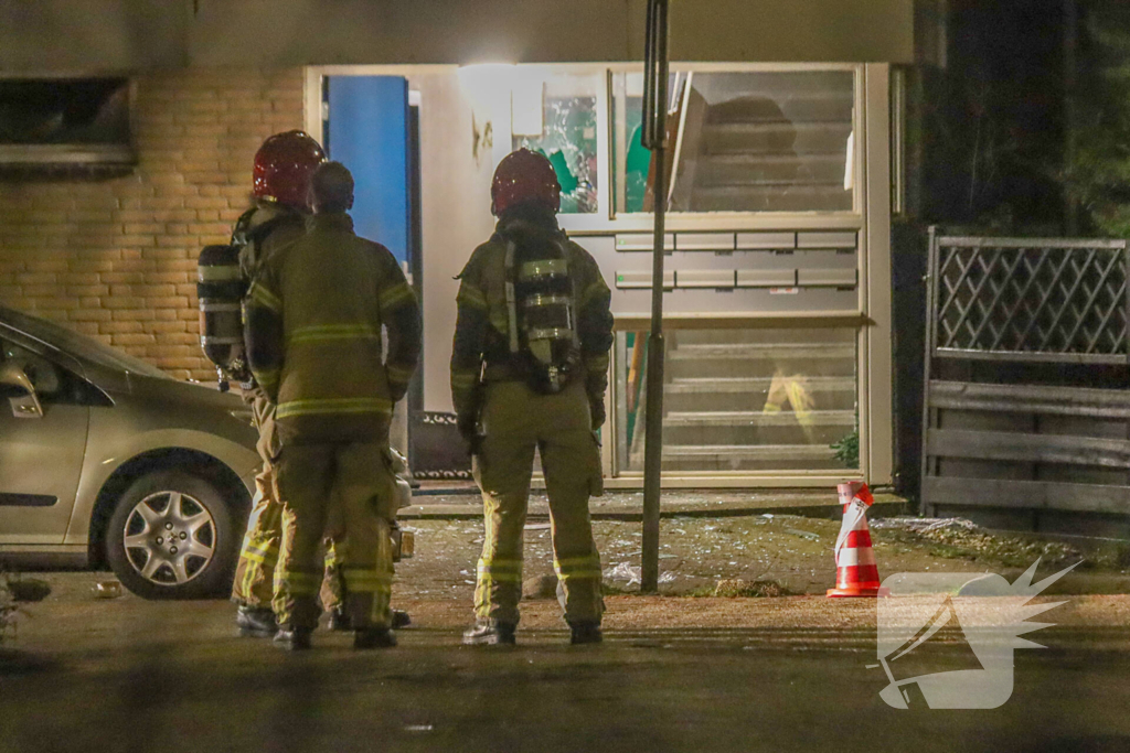 Explosie bij portiek van flatgebouw, brandweer blust vuurhaard