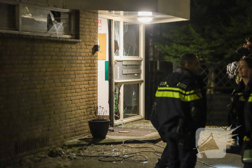 Explosie bij portiek van flatgebouw, brandweer blust vuurhaard