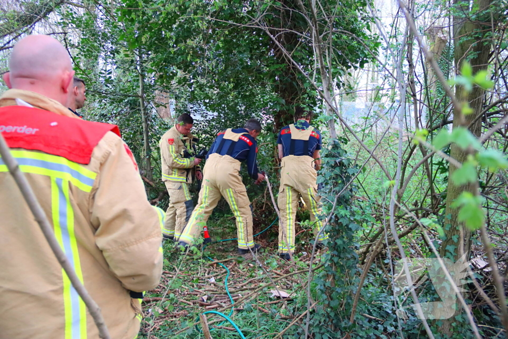 Brandweer dooft brand in boomstam met tuinslang