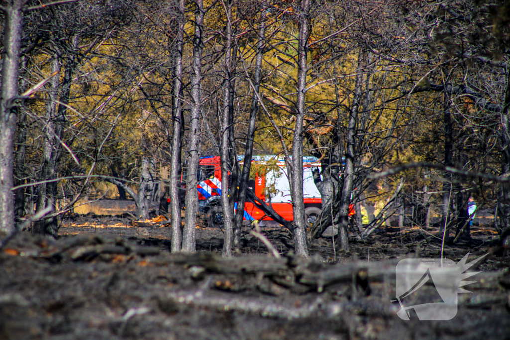 Brandweer blust smeulende resten in afgebrande heidegebied