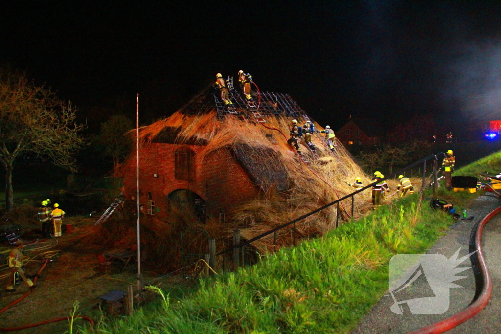 Brandweerlieden trekken rietendak uit elkaar om brand te kunnen bestrijden