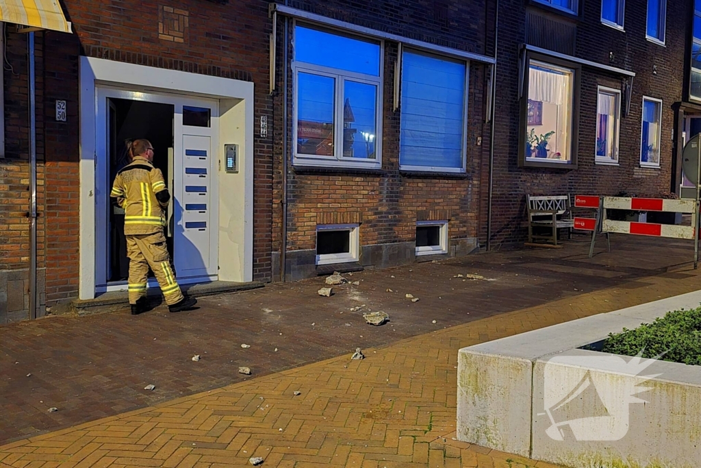 Brokstukken op stoep van gevel