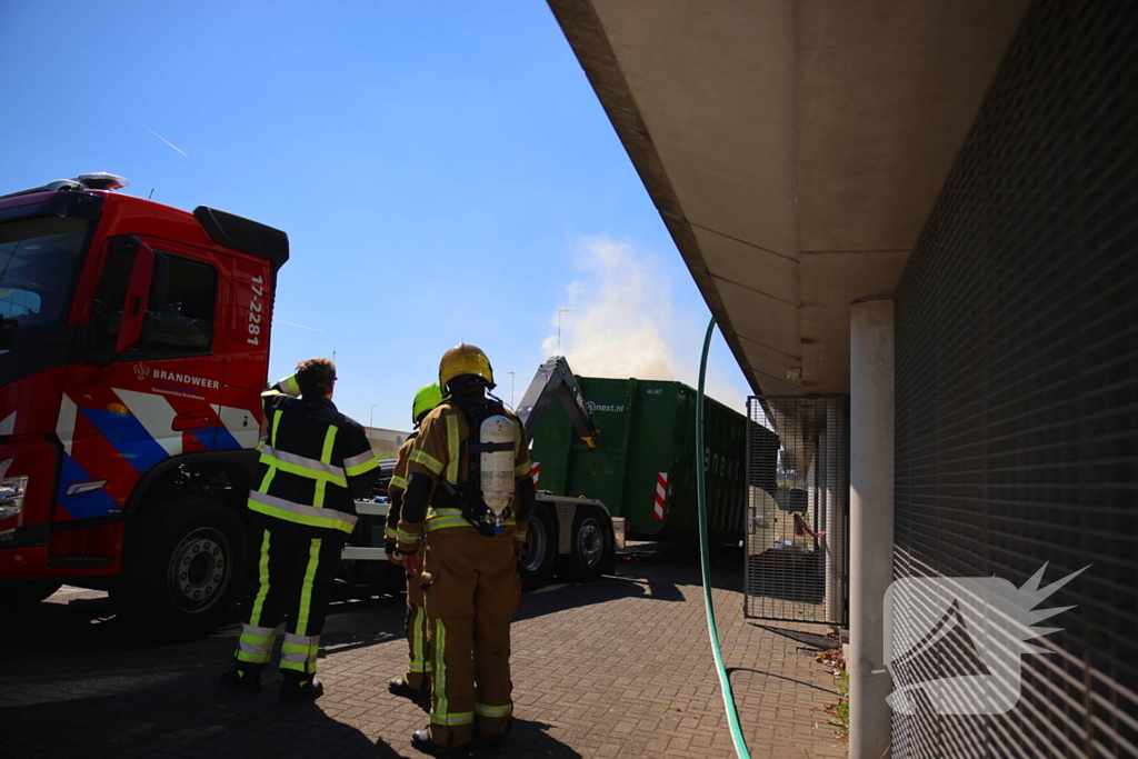 Vlammen slaan uit grote afvalcontainer