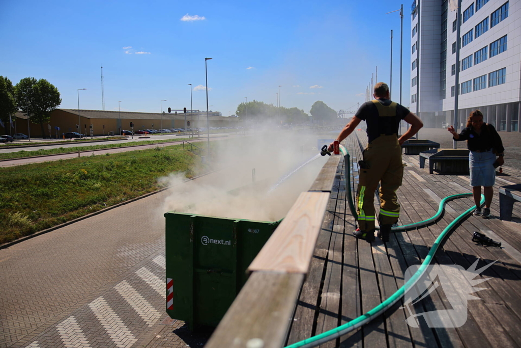 Vlammen slaan uit grote afvalcontainer