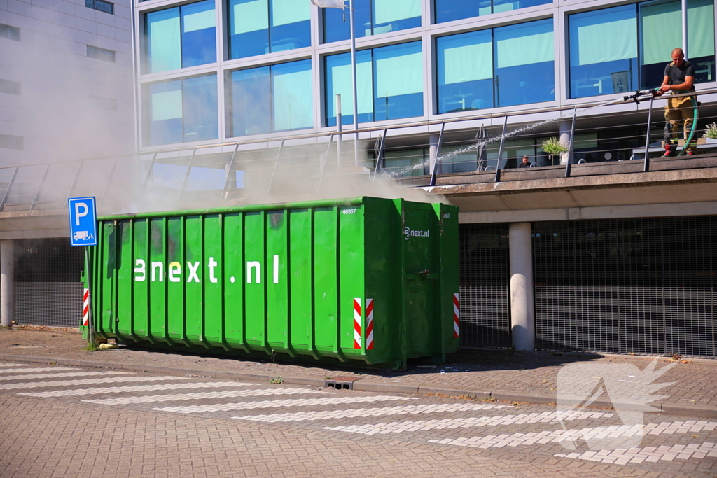 Vlammen slaan uit grote afvalcontainer
