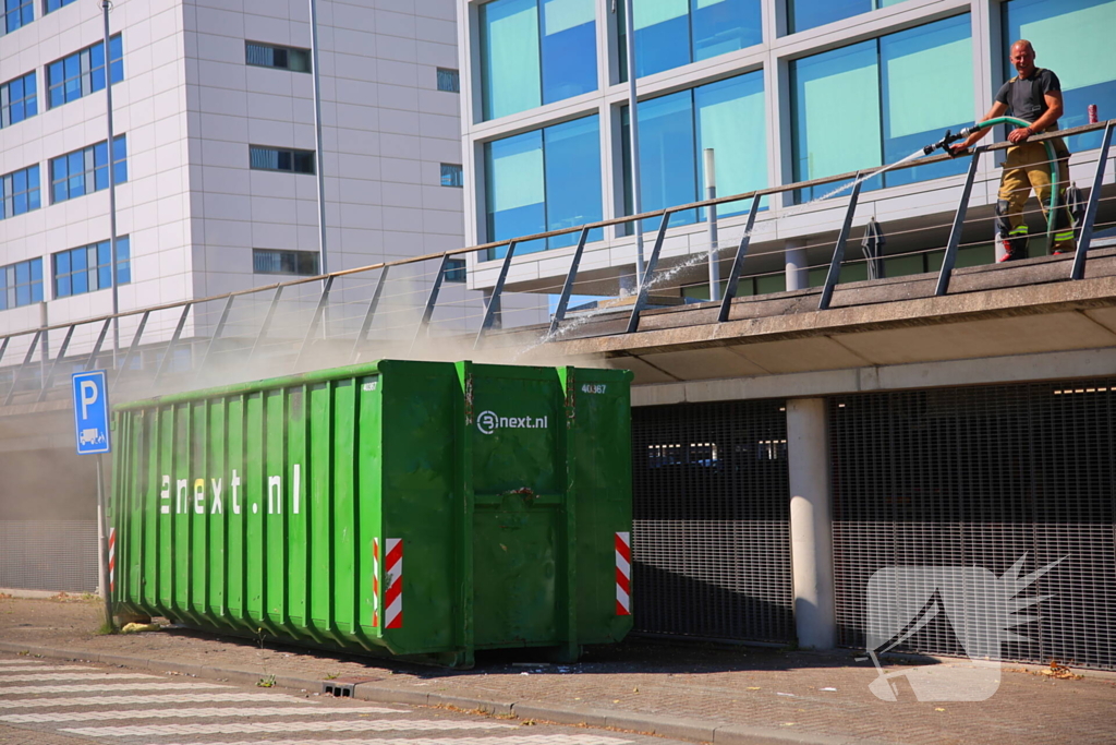 Vlammen slaan uit grote afvalcontainer