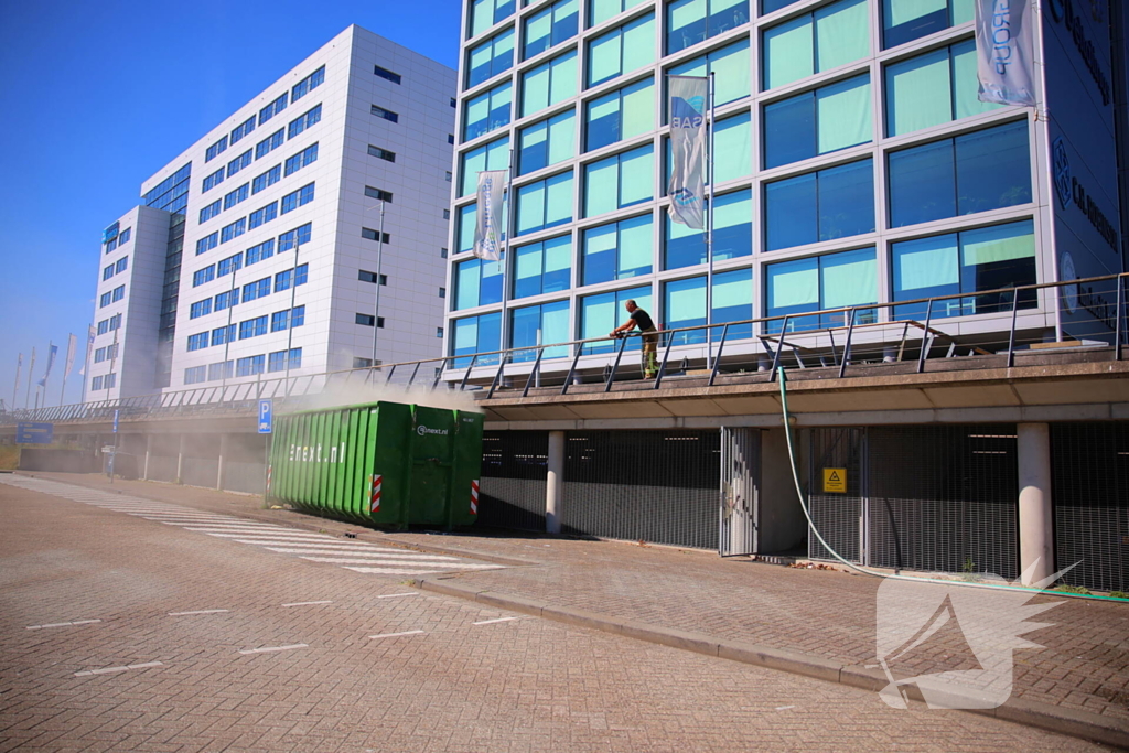Vlammen slaan uit grote afvalcontainer