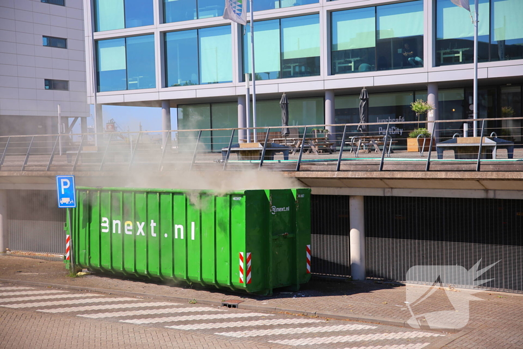 Vlammen slaan uit grote afvalcontainer