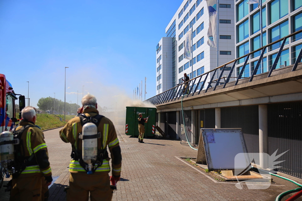 Vlammen slaan uit grote afvalcontainer