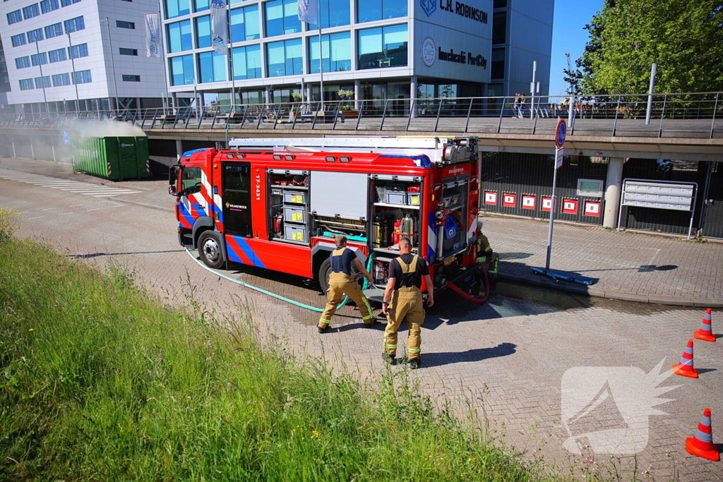 Vlammen slaan uit grote afvalcontainer