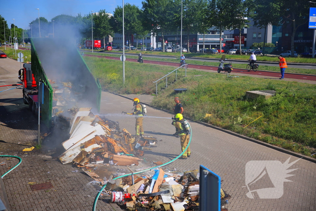 Vlammen slaan uit grote afvalcontainer