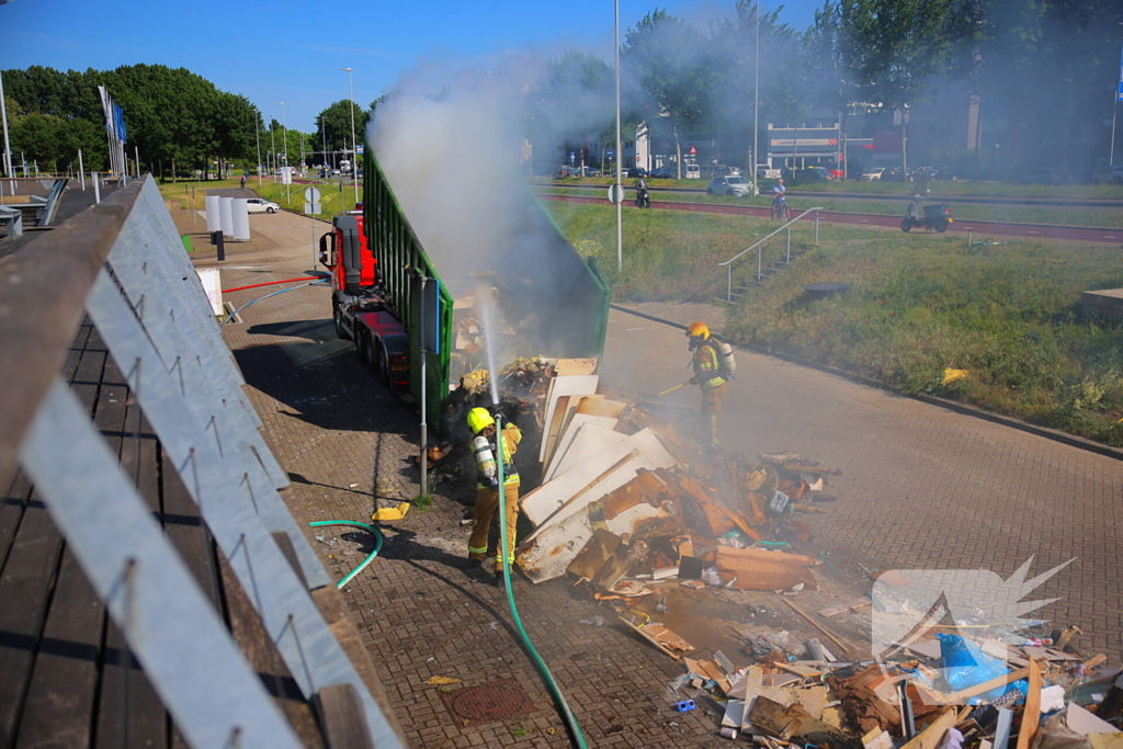 Vlammen slaan uit grote afvalcontainer