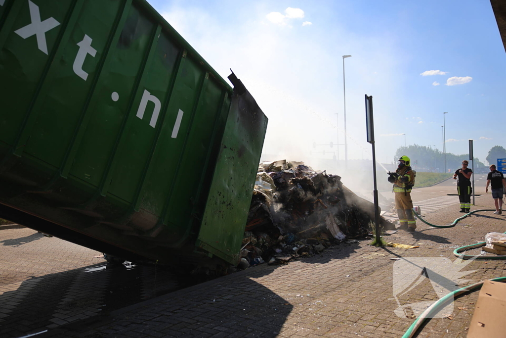 Vlammen slaan uit grote afvalcontainer