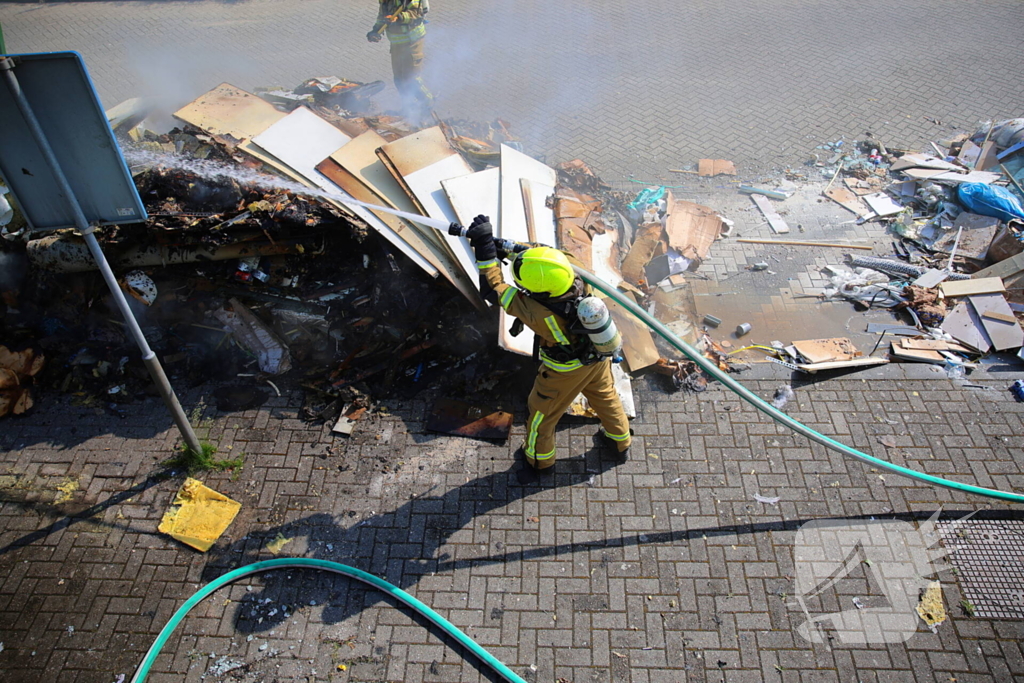 Vlammen slaan uit grote afvalcontainer