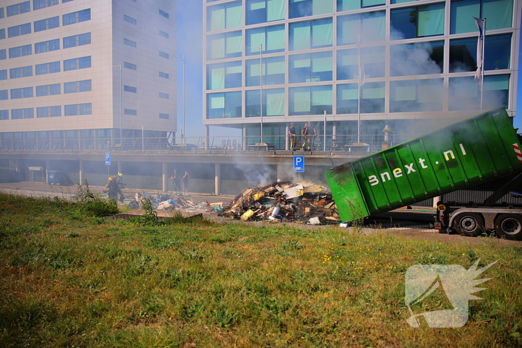 Vlammen slaan uit grote afvalcontainer