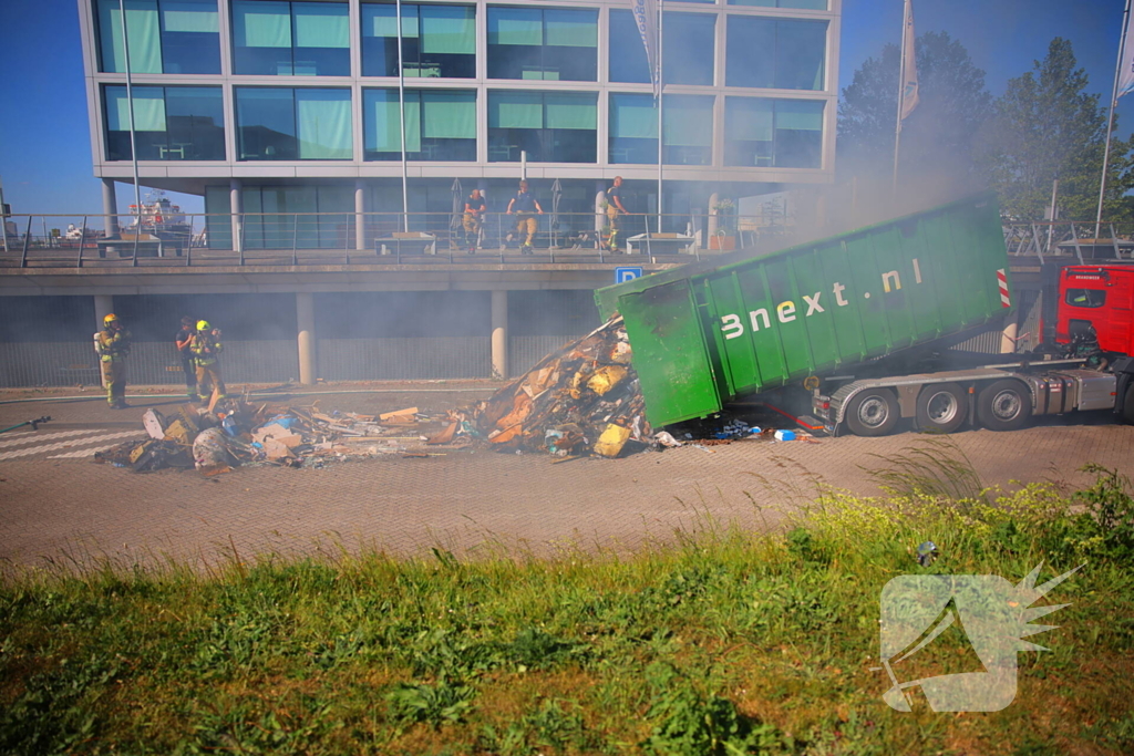 Vlammen slaan uit grote afvalcontainer