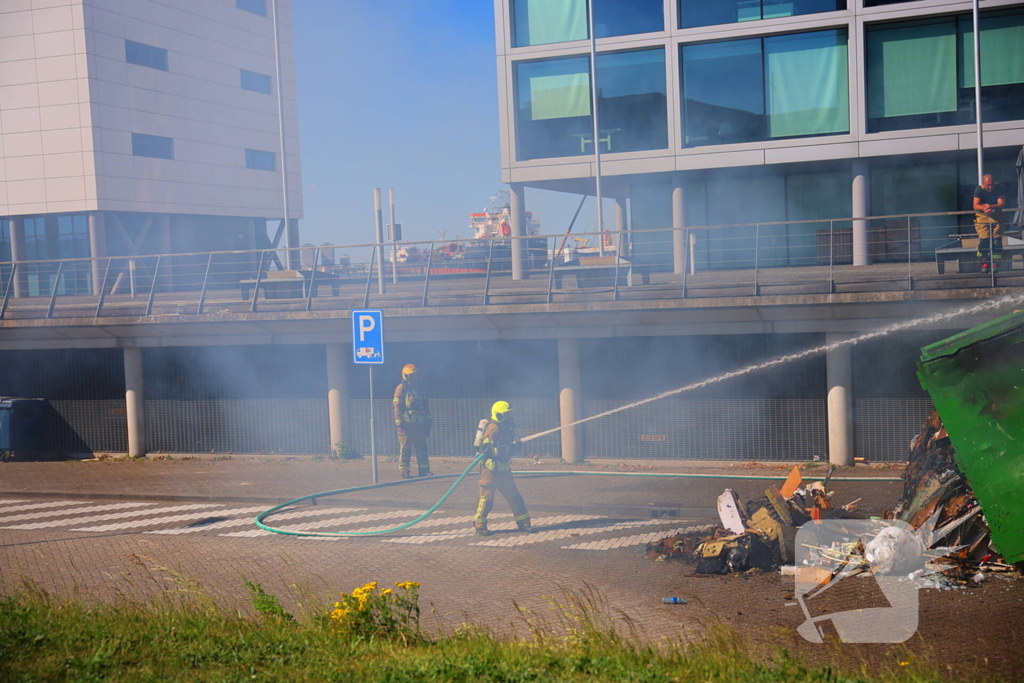 Vlammen slaan uit grote afvalcontainer