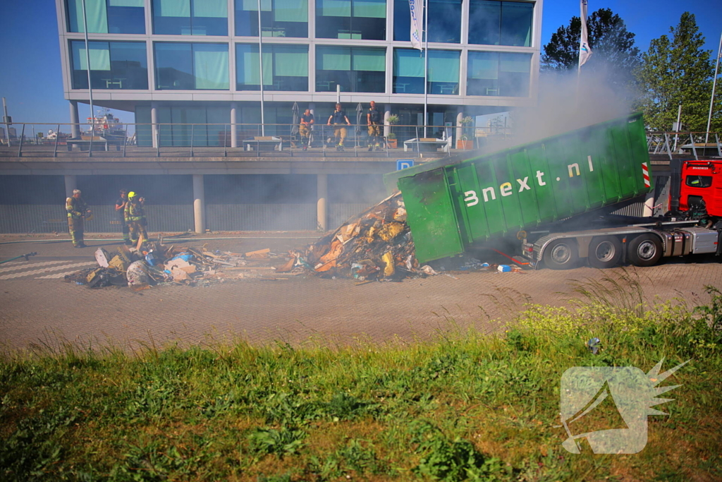 Vlammen slaan uit grote afvalcontainer
