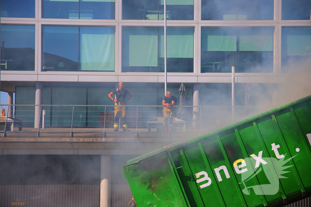 Vlammen slaan uit grote afvalcontainer