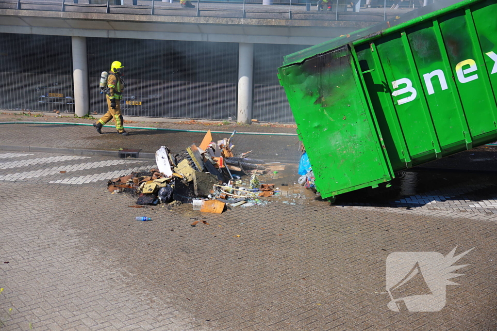 Vlammen slaan uit grote afvalcontainer