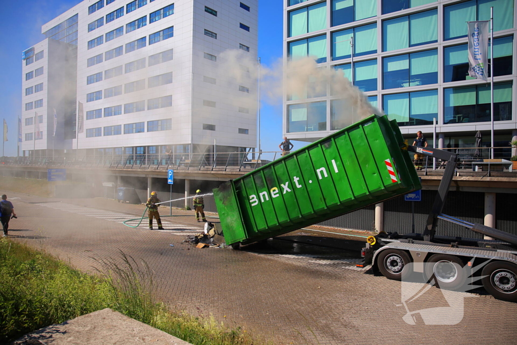 Vlammen slaan uit grote afvalcontainer