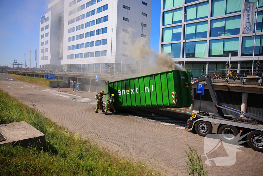 Vlammen slaan uit grote afvalcontainer